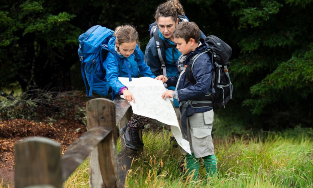 Family using GPS devices to find a geocache in a forest.